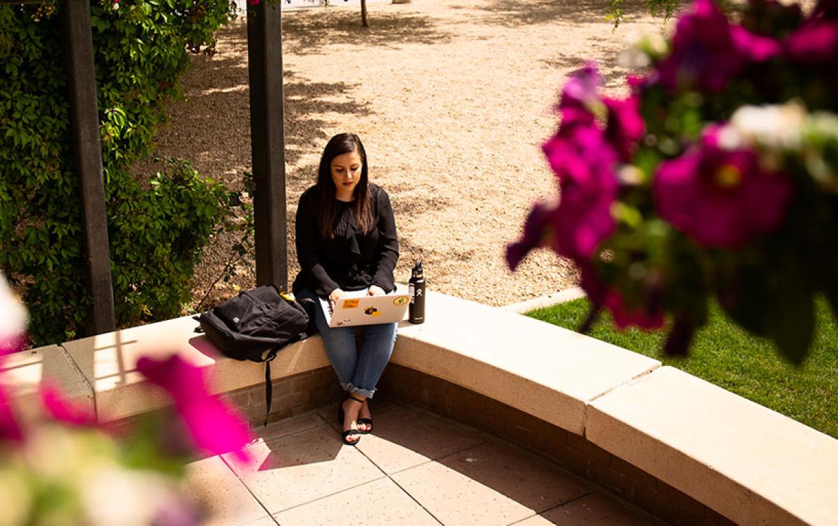 student sitting outside using laptop