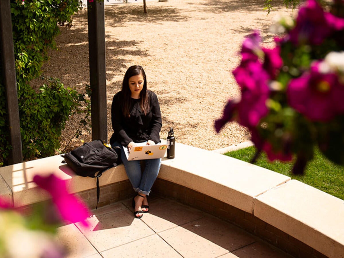 student sitting outside using laptop