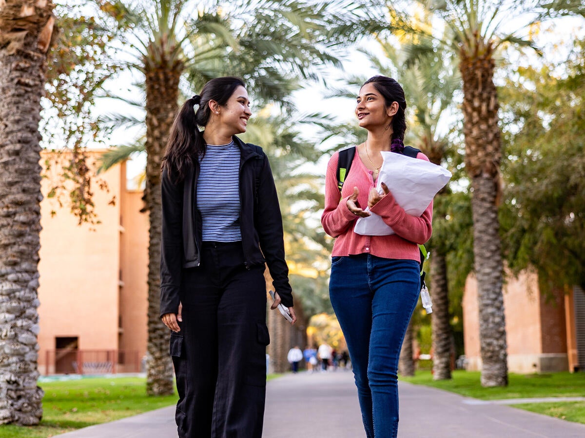 Two students strolling down park walk