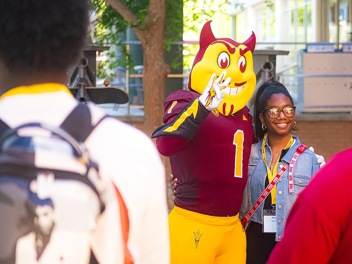 A student posing with the Sparky mascot 